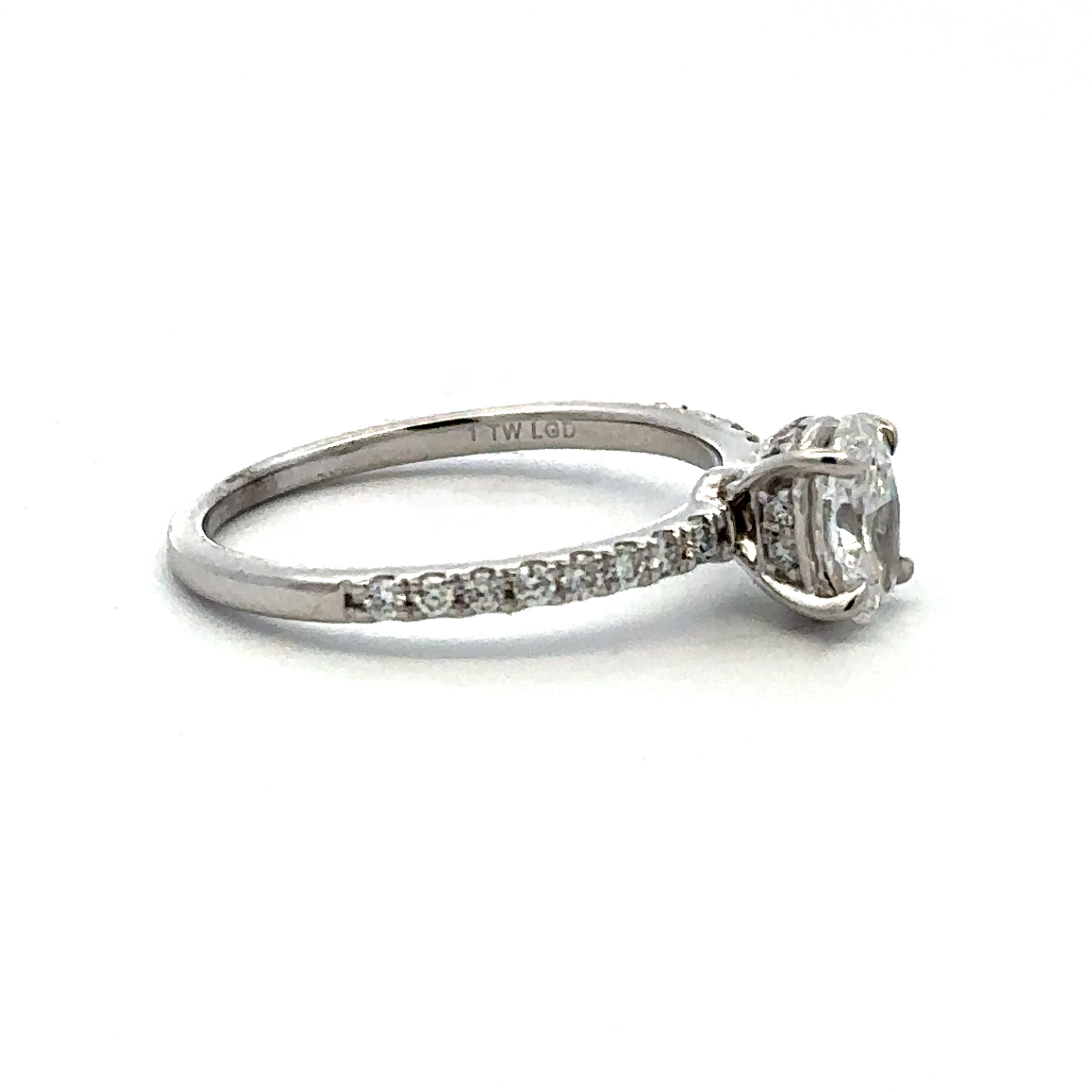A silver-toned diamond ring with a round-cut center stone and a pavé band, shown on a plain white background.