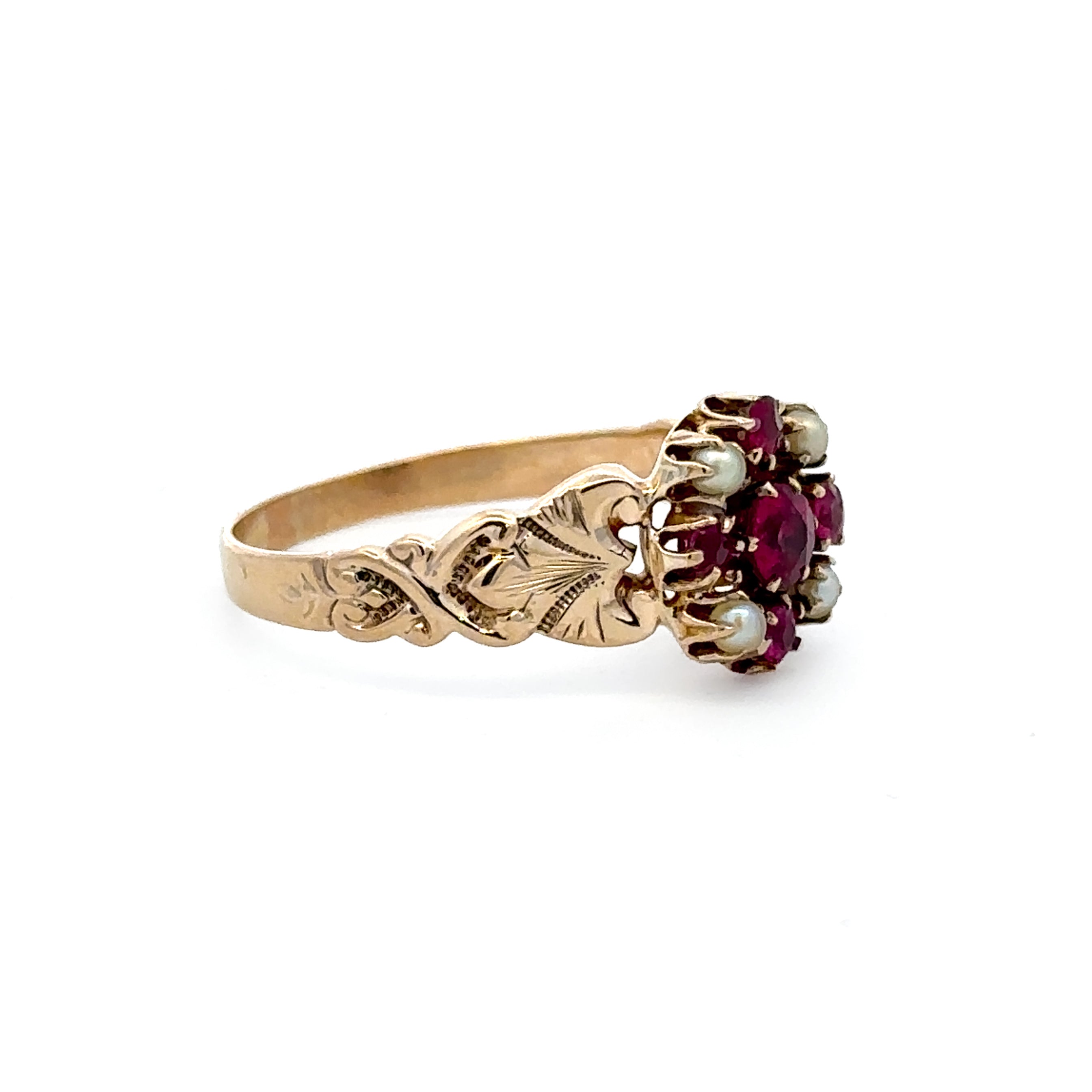An antique-style gold ring featuring a floral cluster setting with deep red gemstones and pale blue-green pearl accents, shown on a plain white background.