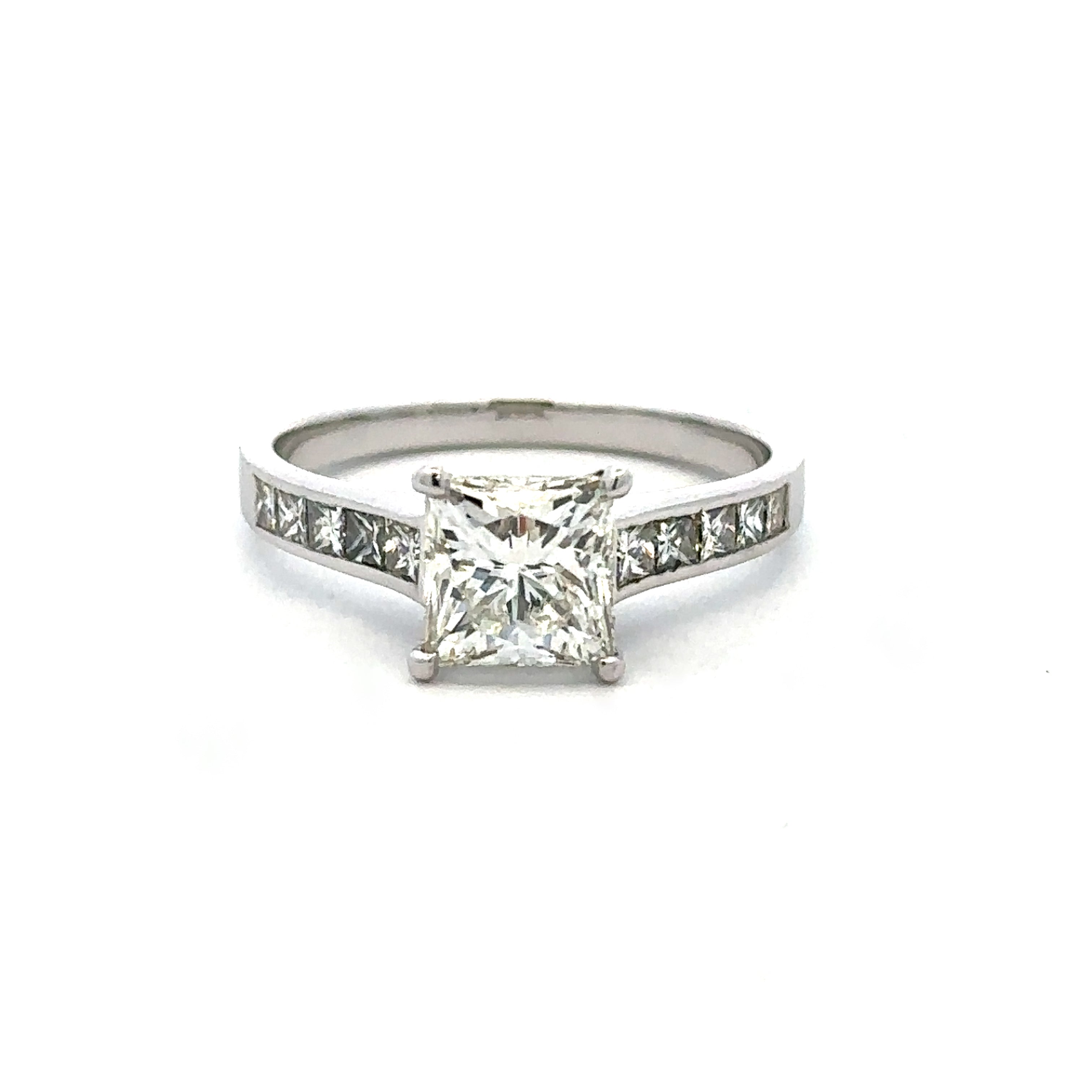 A classic diamond engagement ring featuring a princess-cut center stone in a four-prong setting, with a silver-colored band adorned with small pavé-set diamonds on either side, shown against a plain white background.