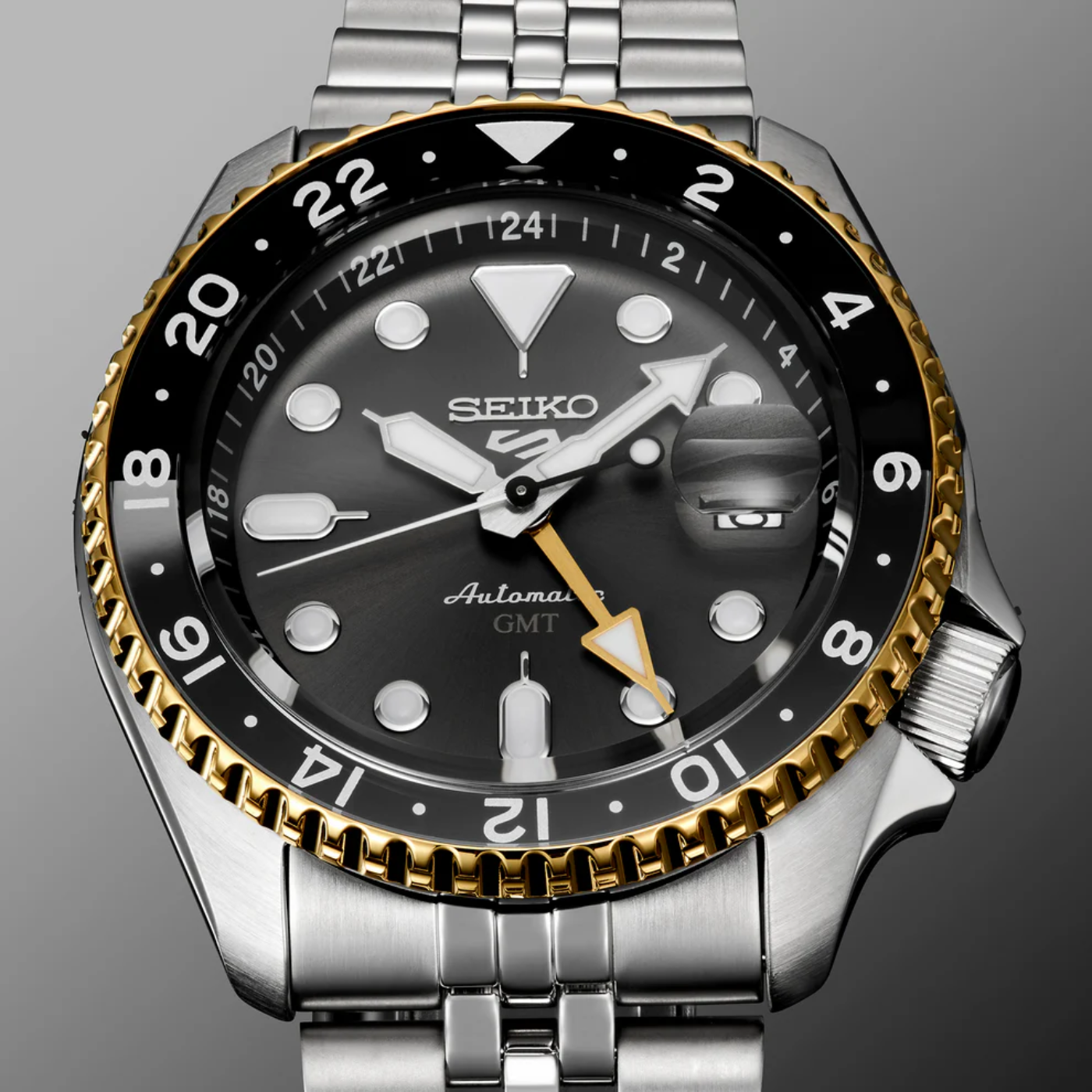 Seiko watch with black dial and gold accents on a gray background