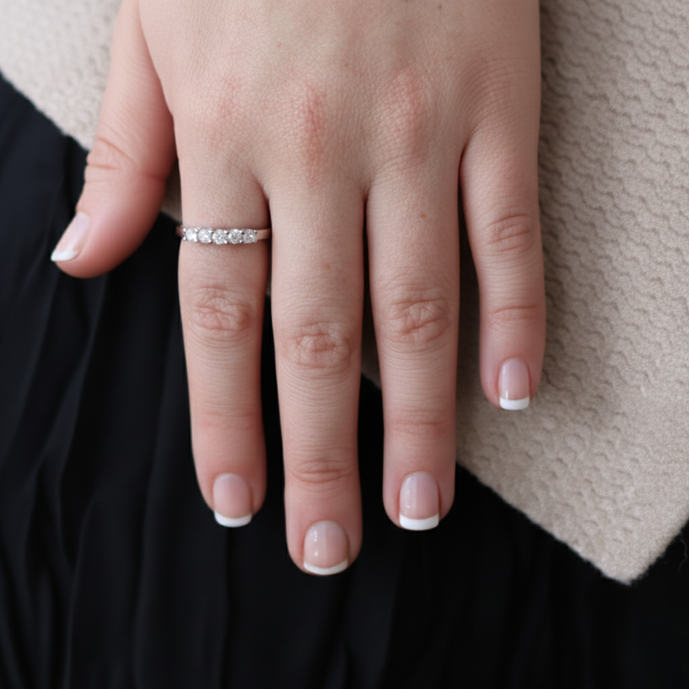 Close-up of a hand wearing a diamond ring with a neutral background