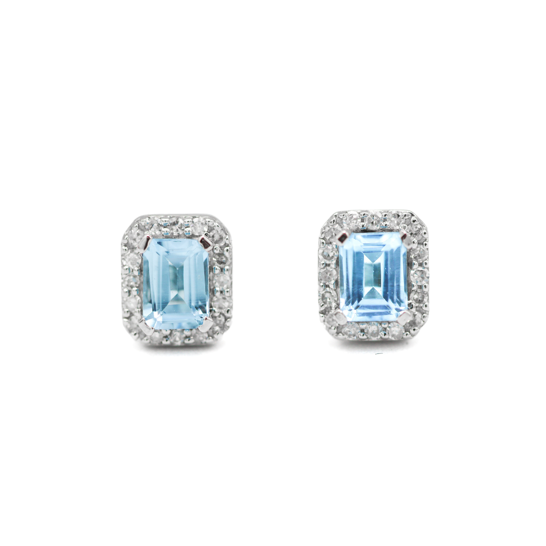 Front facing view of 10K White Gold Emerald-Cut Swiss Blue Topaz & 1/10CT. Diamond Halo Stud Earrings on a white background.