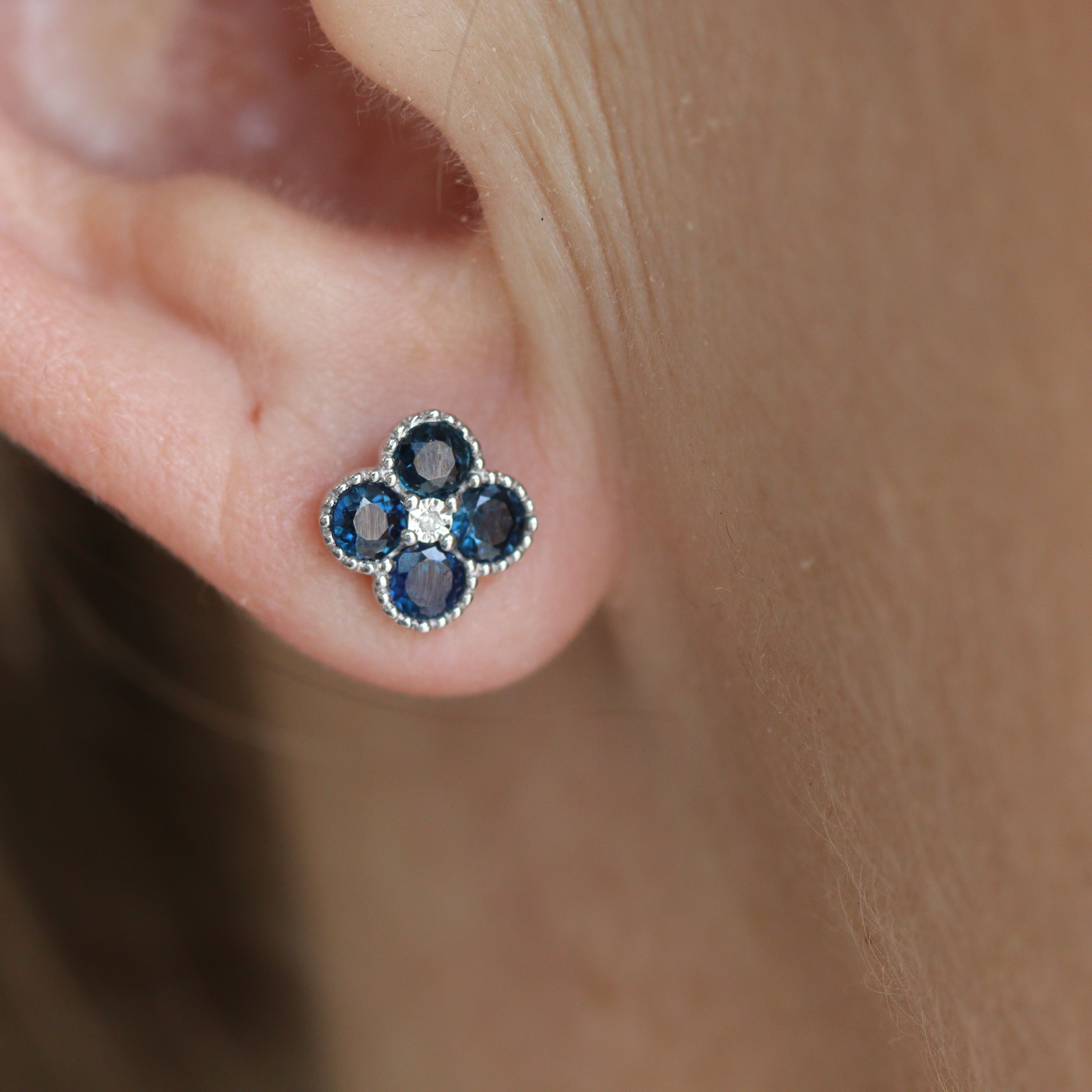 14K White Gold 1CTW. Sapphire & 1/50CTW. Diamond Clover Stud Earrings closeup on a model's ear.
