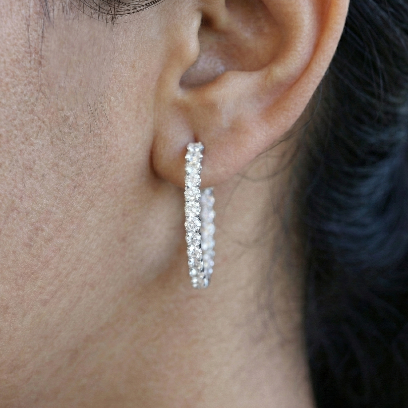 Close-up of an ear wearing a diamond earring with a blurred background