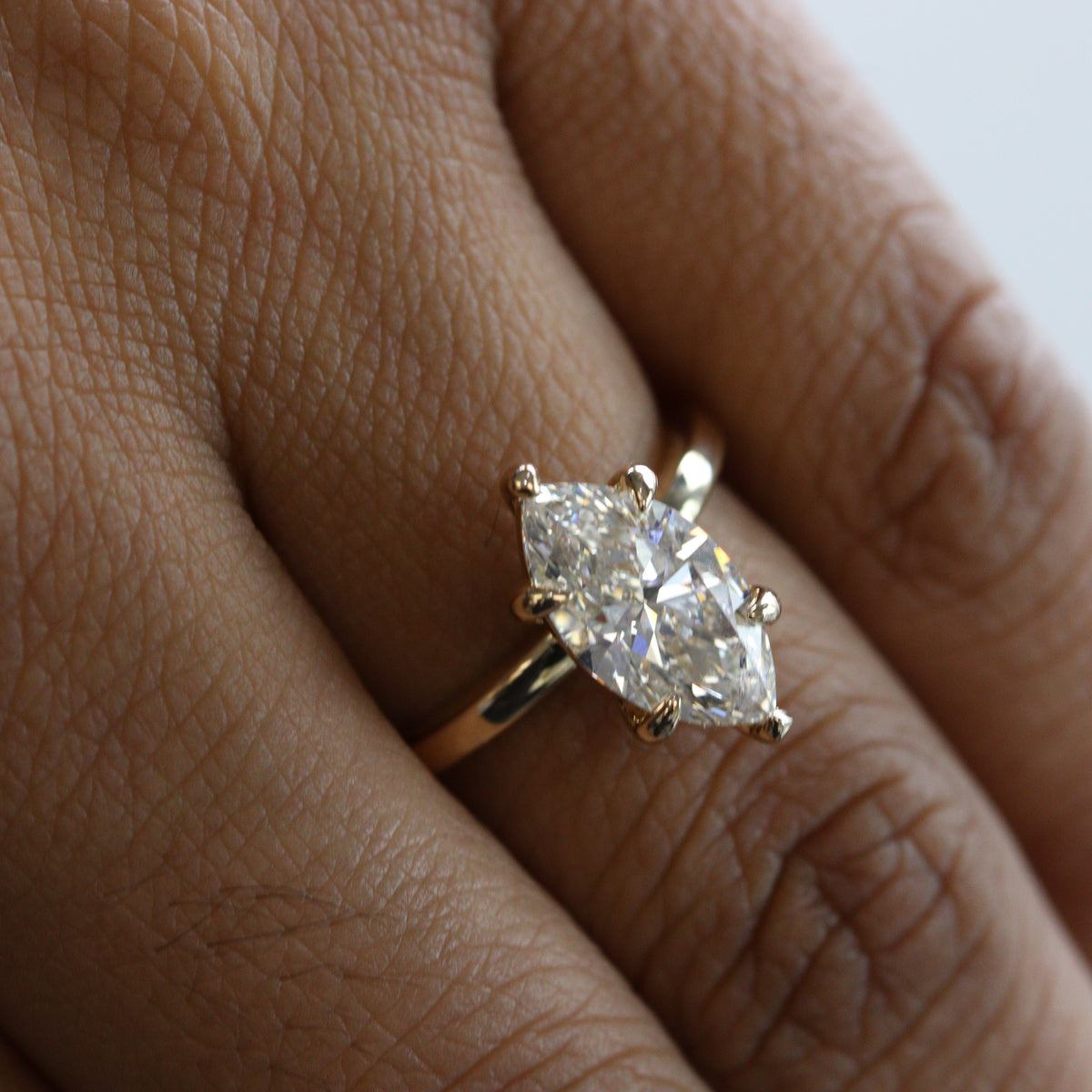 Gold ring with a marquise-shaped diamond on a finger