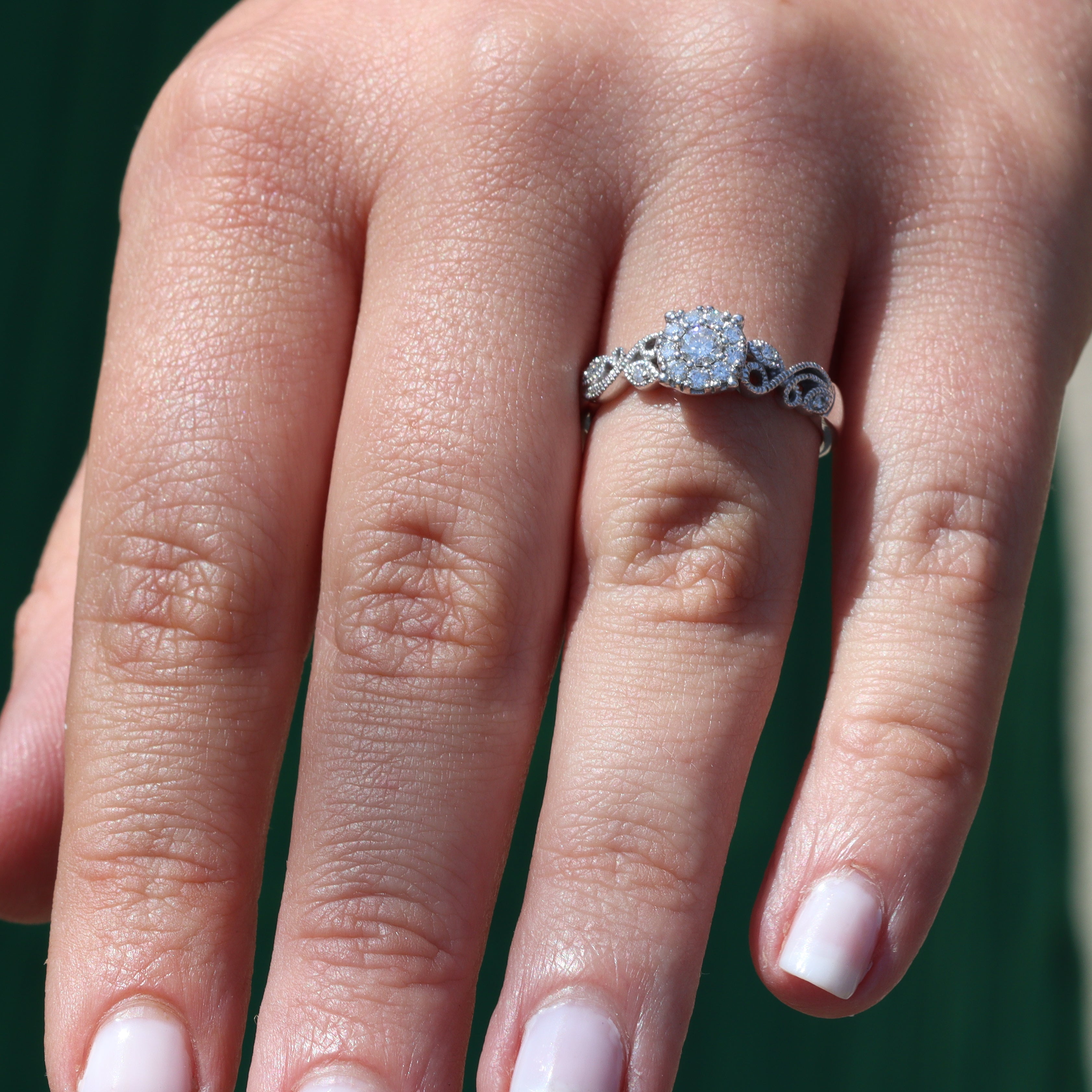 Close-up of a hand wearing a diamond ring with a blurred background