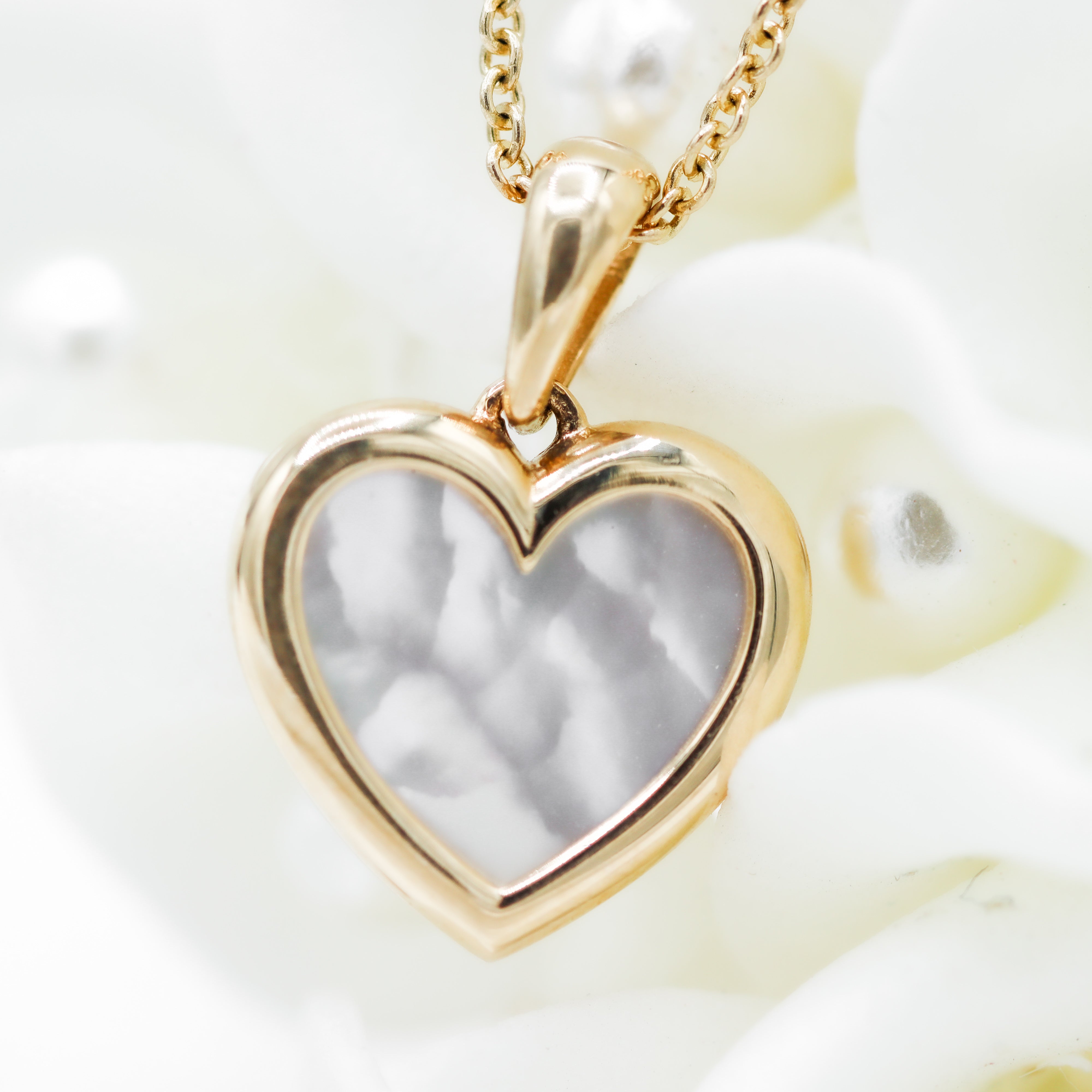 Yellow Gold Mother Of Pearl Heart Pendant Necklace laying on flowers