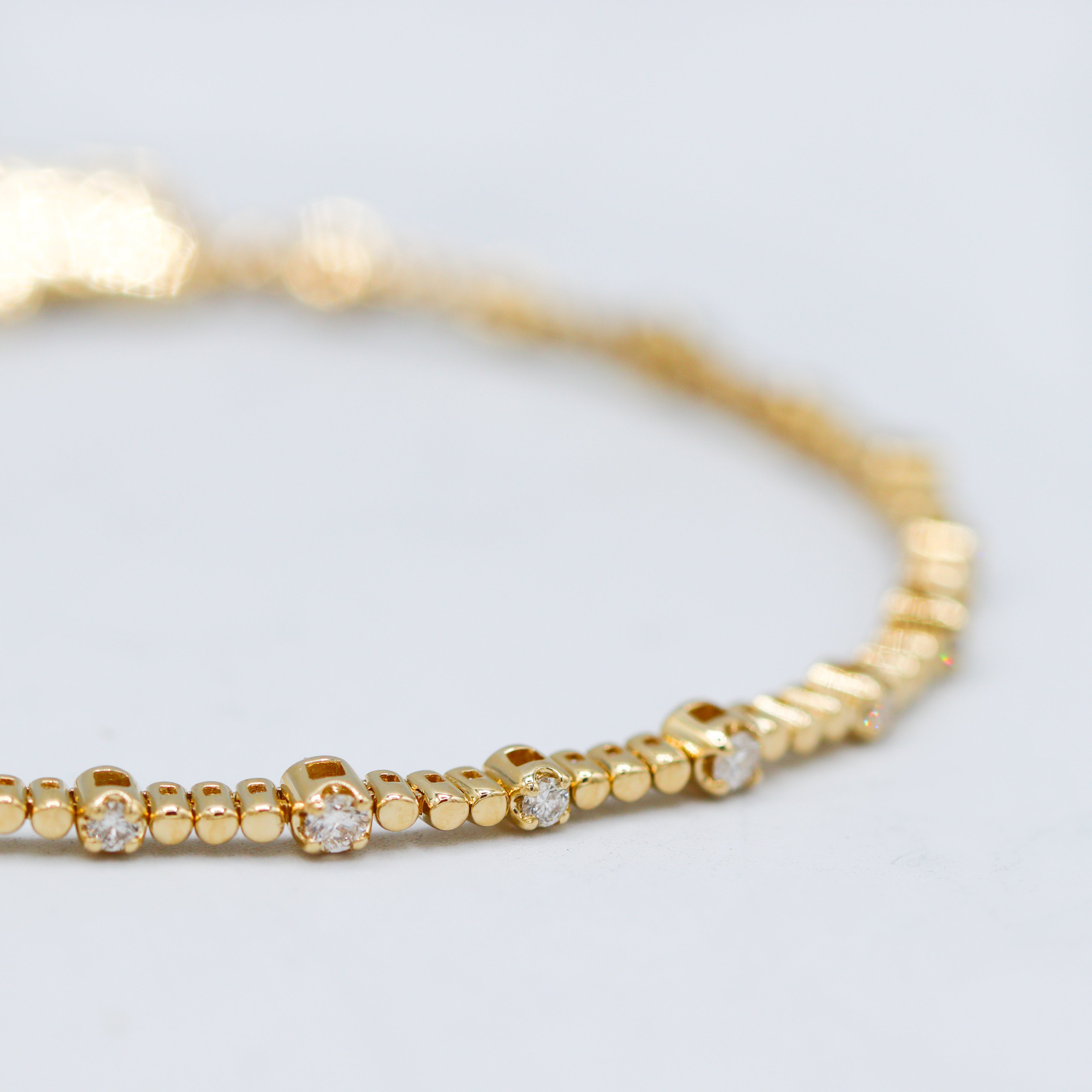 14K Yellow Gold 0.61CTW. Diamond Beaded Station Tennis Bracelet close up on a gray background