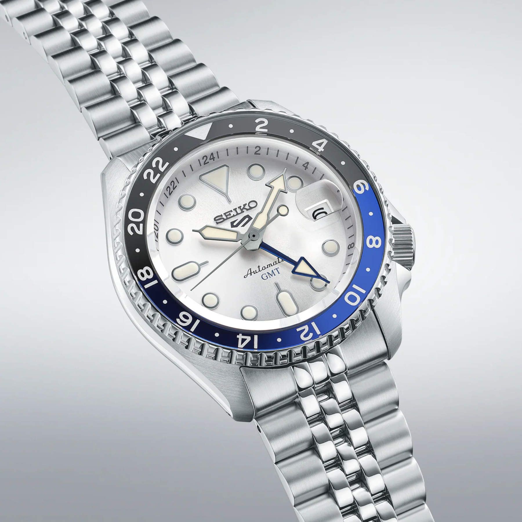 Silver Seiko watch with blue bezel on a light gray background
