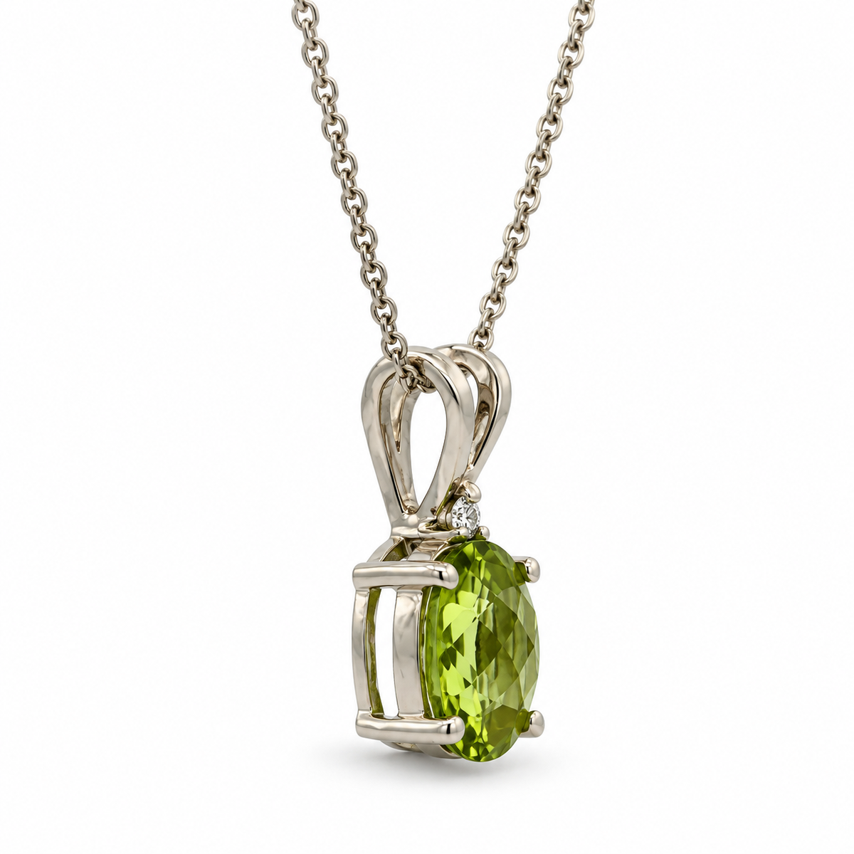 Side view of 14K white gold oval peridot and diamond pendant necklace on a white background