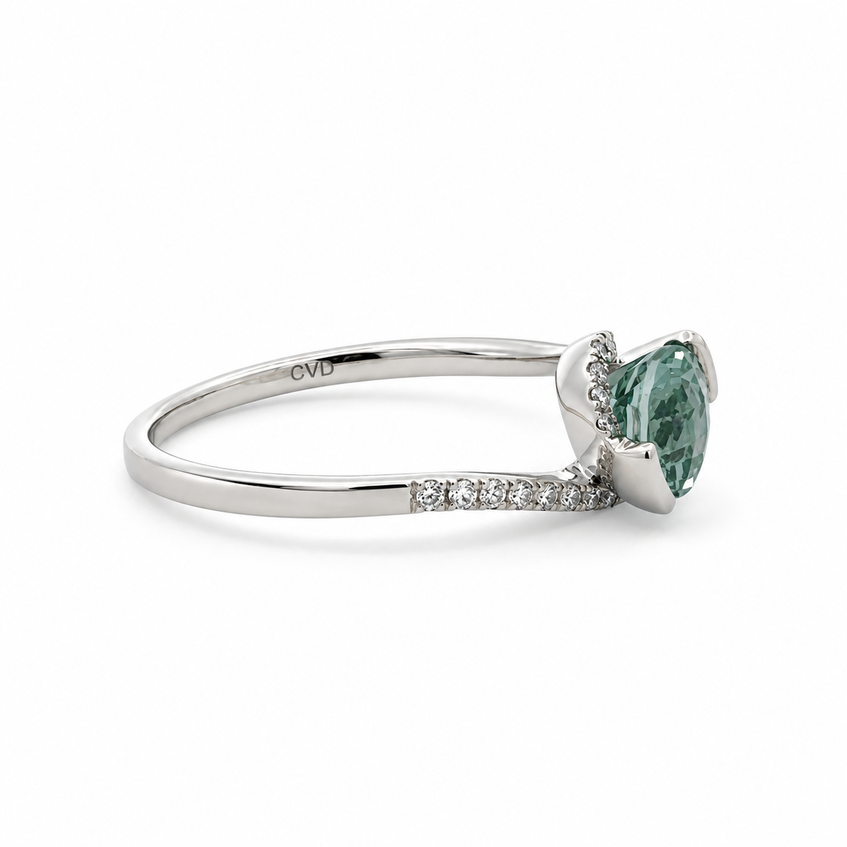 Side view of a white gold green sapphire ring showing the partial bezel setting and sweeping diamond-accented shoulders.