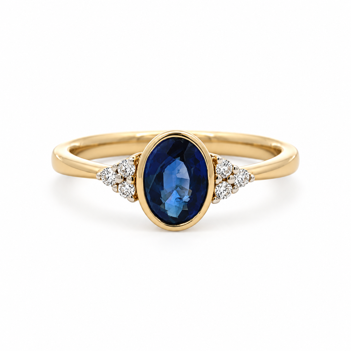 Front view of a 14K yellow gold ring with an oval blue sapphire in a bezel setting and diamond accents on both shoulders.