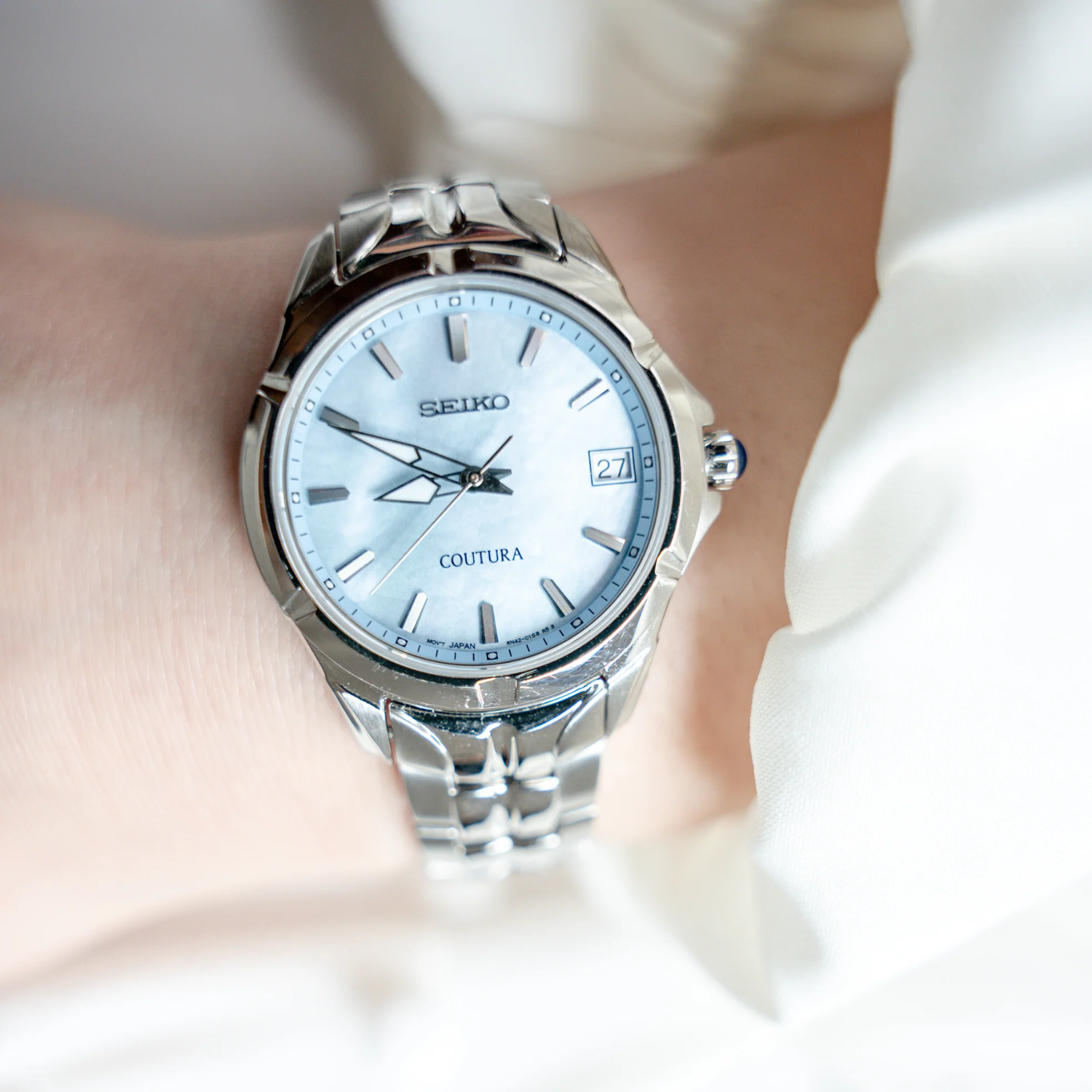 Silver Seiko watch on a wrist with a blurred background