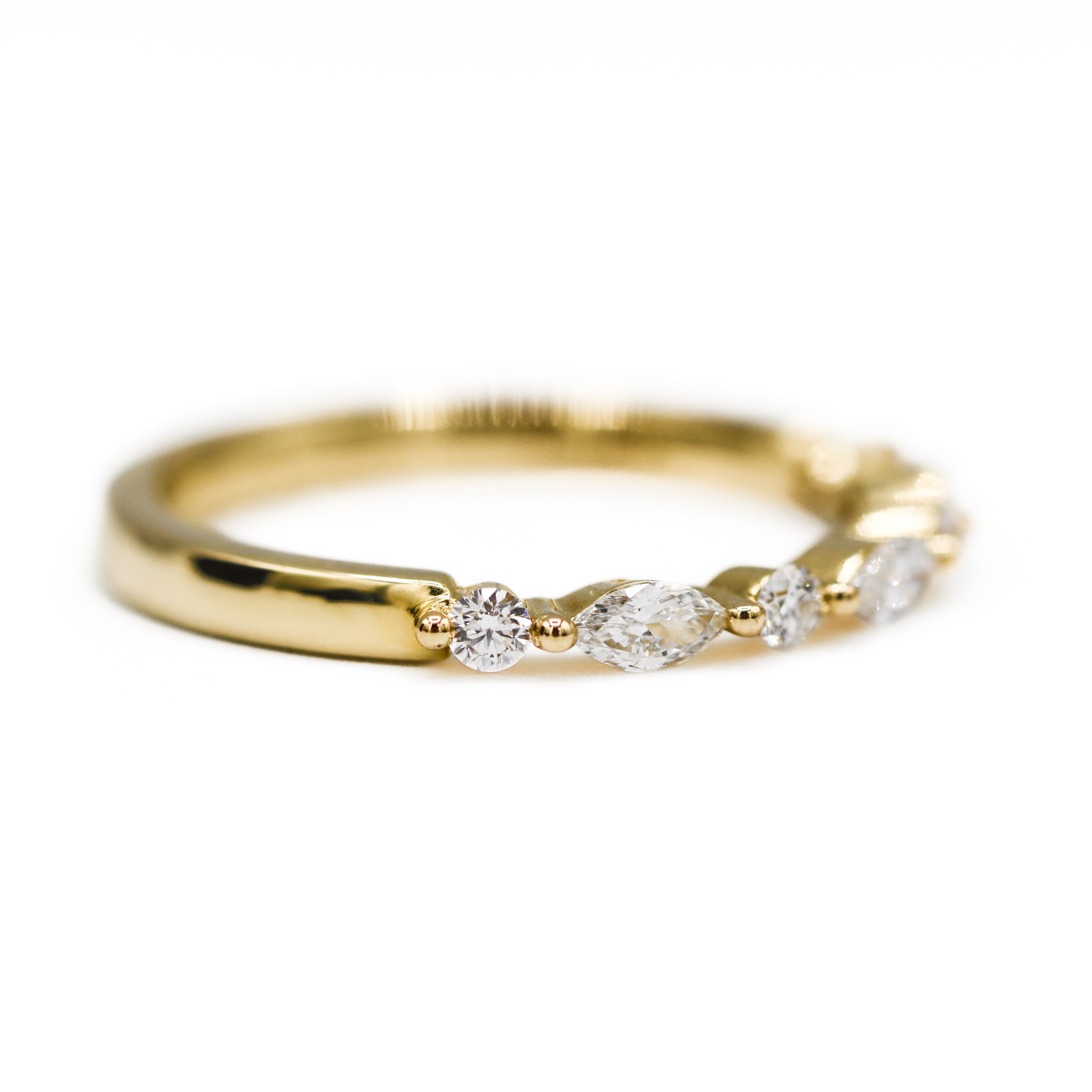 Angled to the right view of 14K Yellow Gold 0.5CTW. Lab-Grown Diamond Marquise & Round Wedding Band laying flat on a white surface and background.