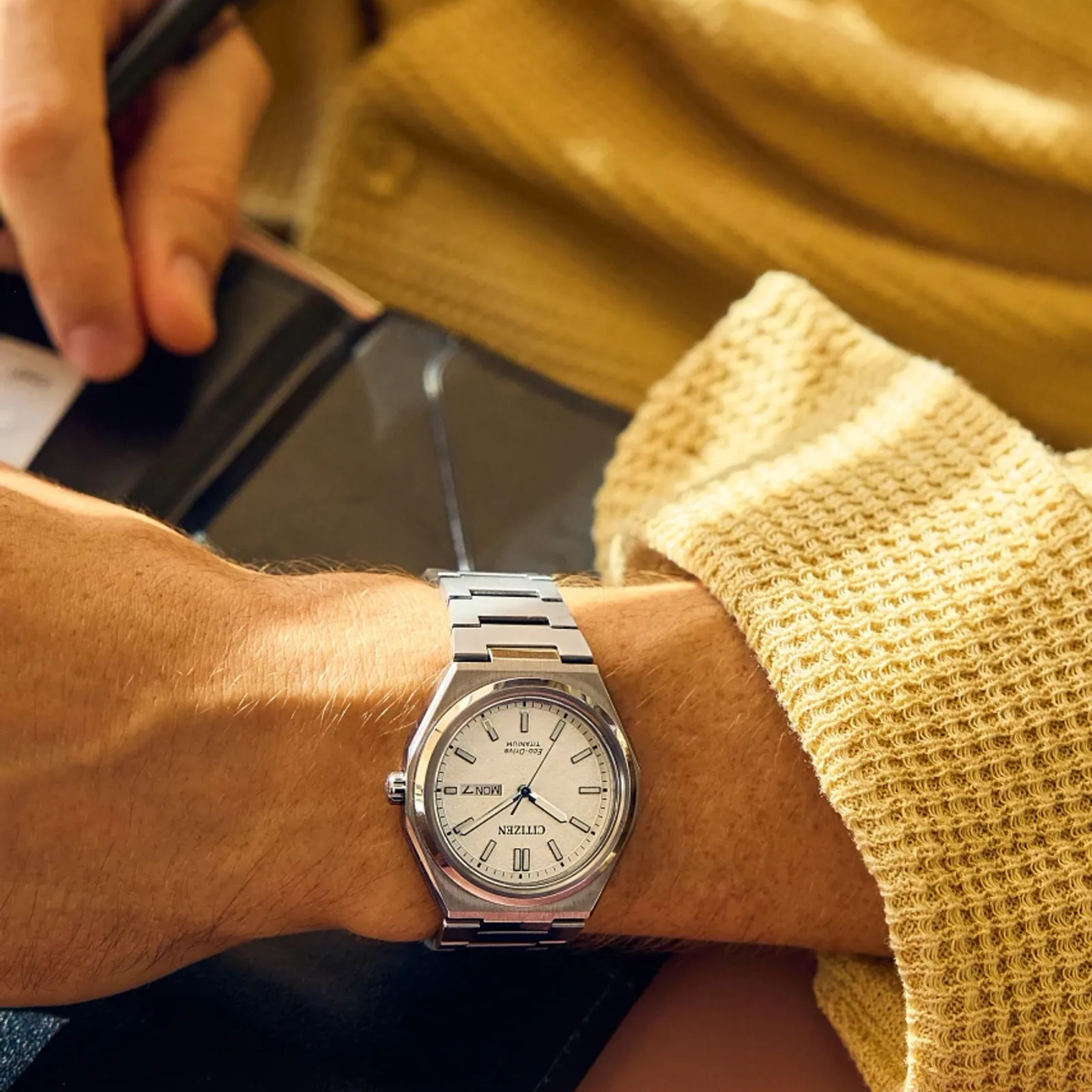 Close-up of a person's wrist wearing a silver watch with a blurred background