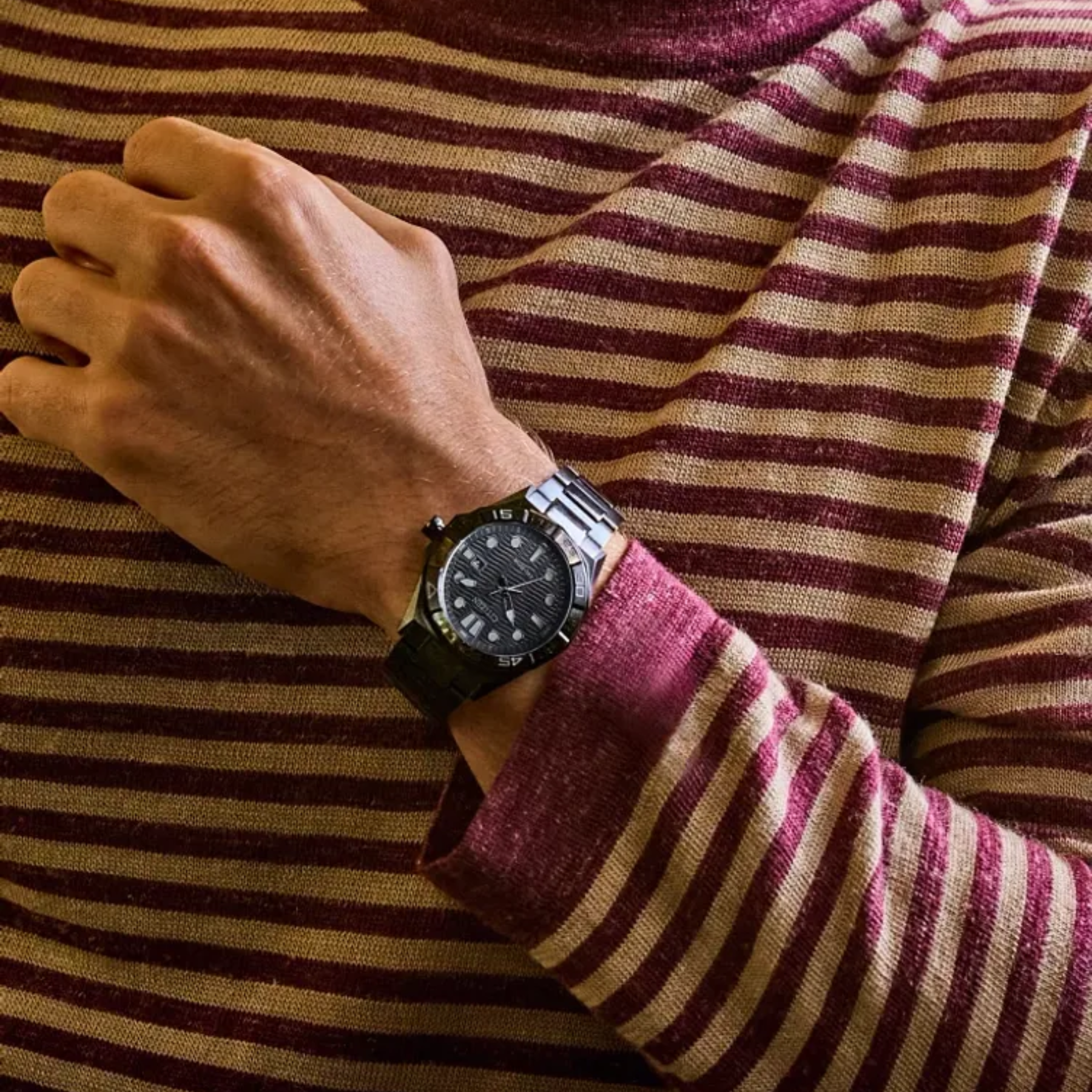 Close-up of a person wearing a striped sweater and a watch with a blurred background