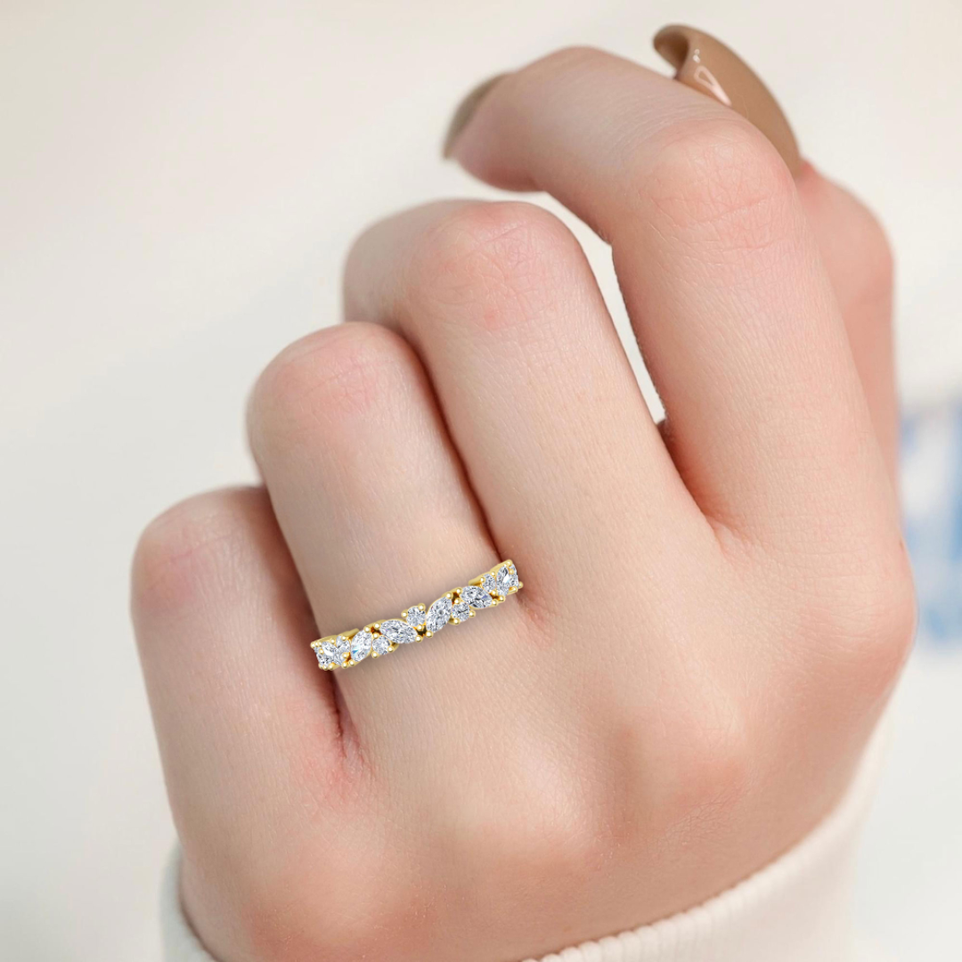 Silver ring with small diamonds on a finger against a neutral background