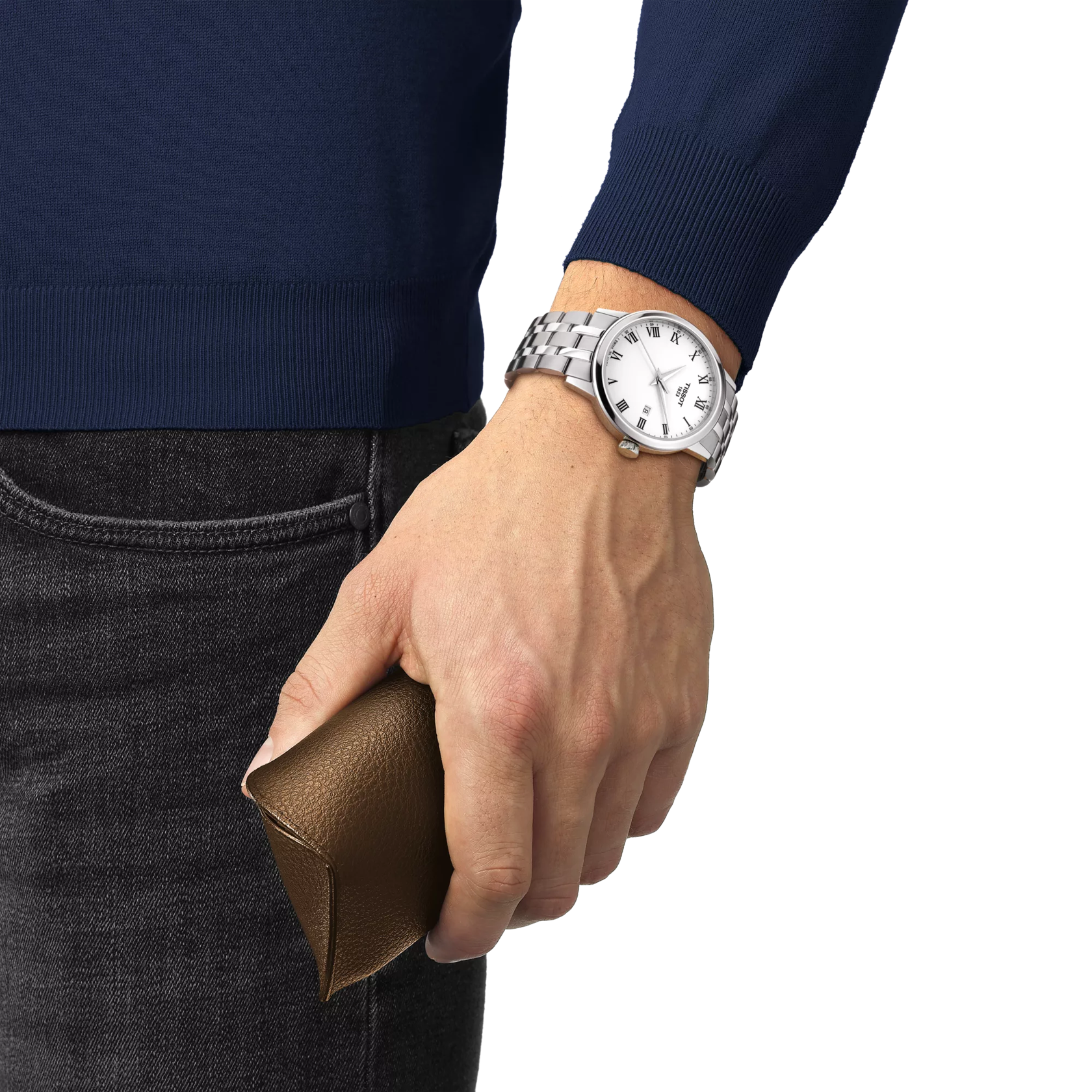 Hand wearing a silver watch holding a brown leather wallet, with a blue sweater and dark jeans.