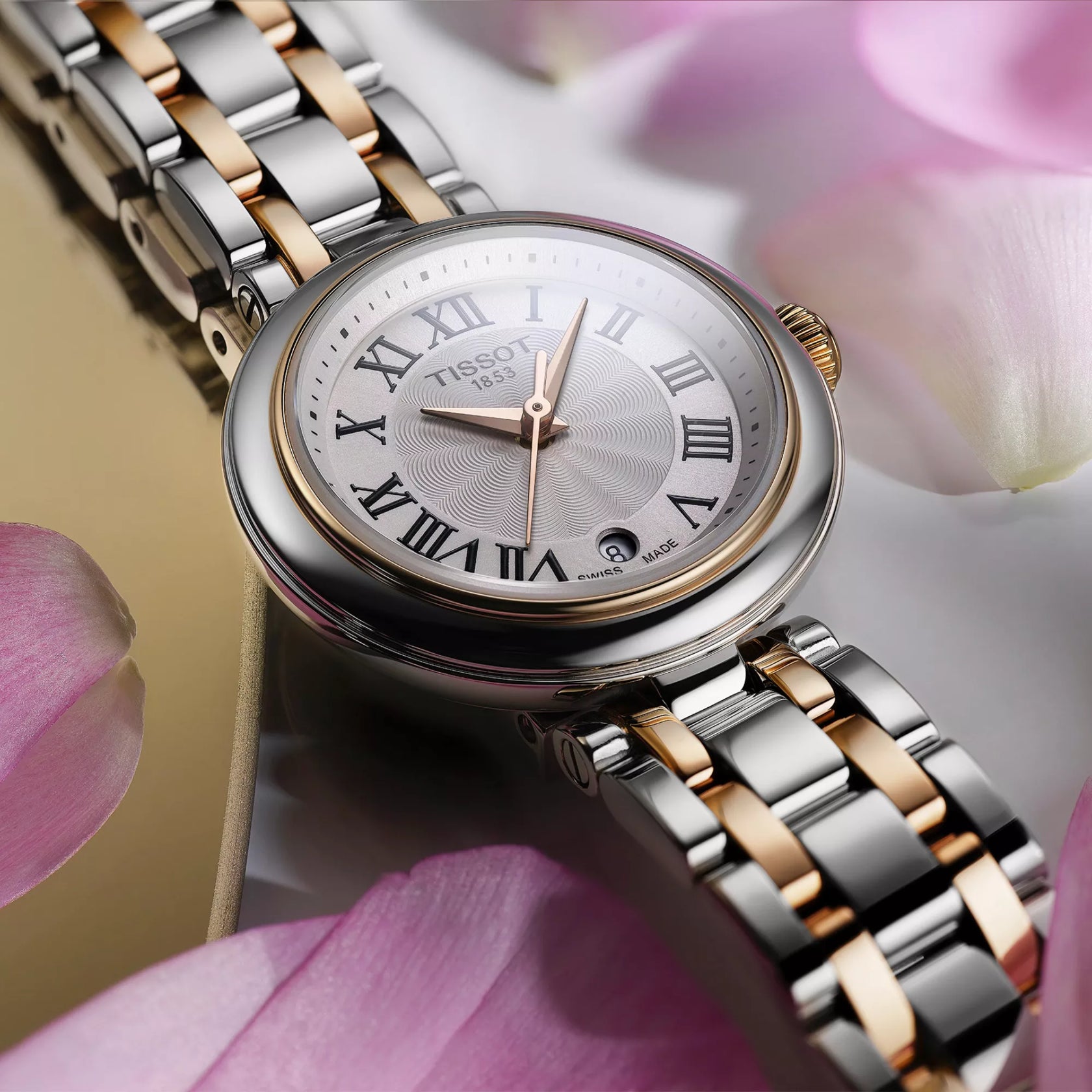 Silver and rose gold watch with Tissot logo on a pink floral background