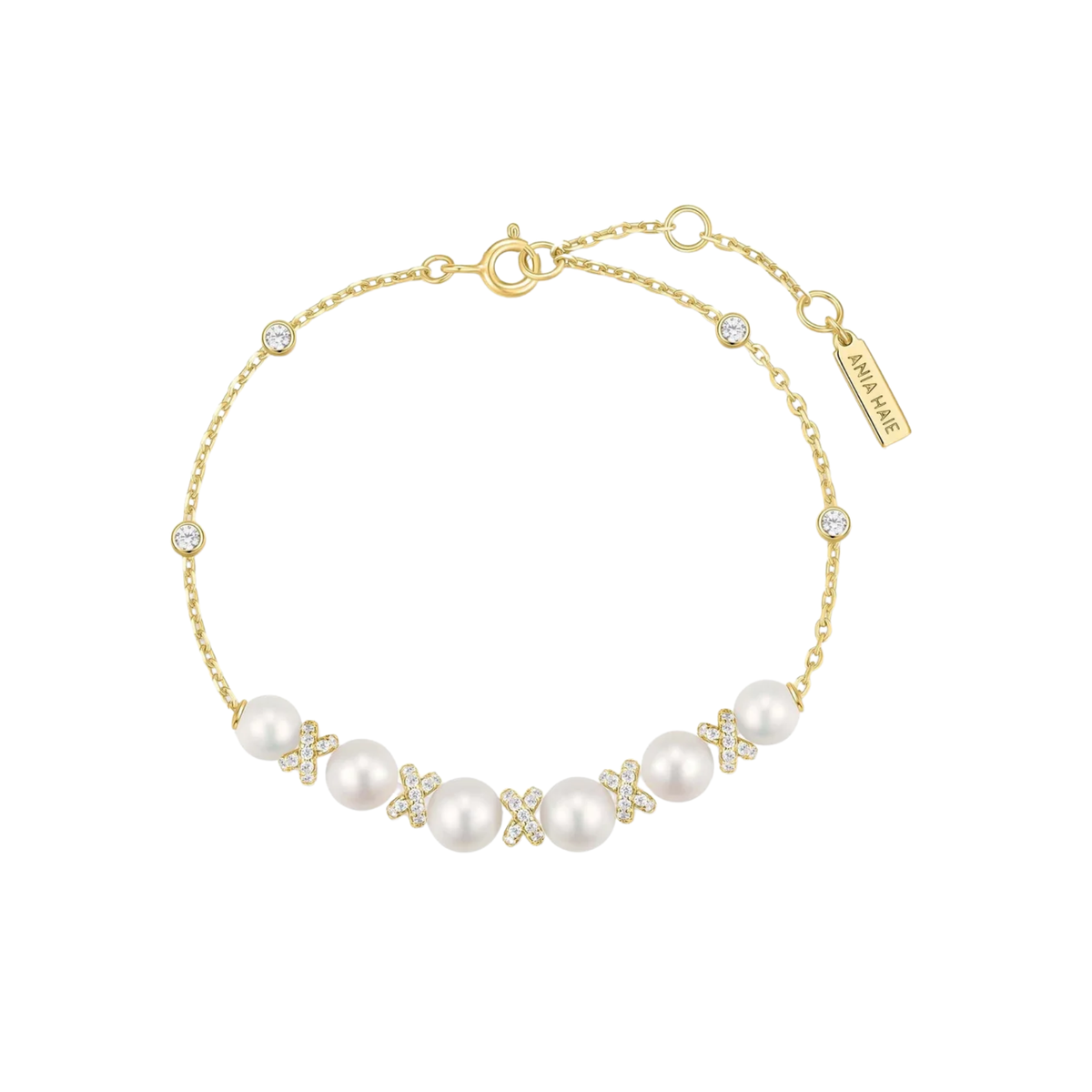 A delicate gold chain bracelet featuring a row of white pearls and small gold floral motifs, accented with clear rhinestones. The bracelet has a lobster clasp, an adjustable extender chain, and a branded tag that reads 'AMIRI KARRA'.