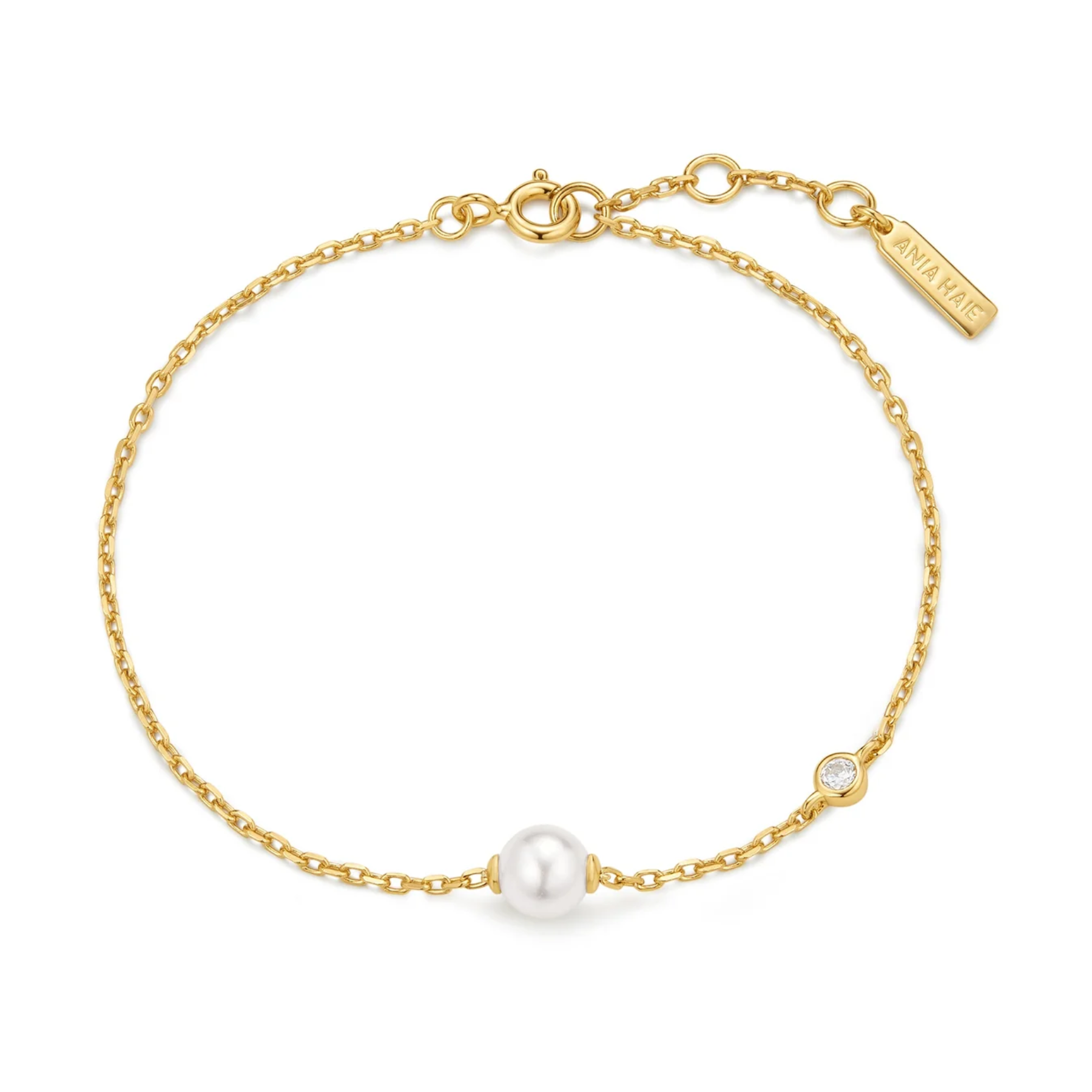 A delicate gold chain bracelet featuring a central white pearl and a small bezel-set clear stone, with a gold clasp and an engraved tag reading 'SHAWKAT'.