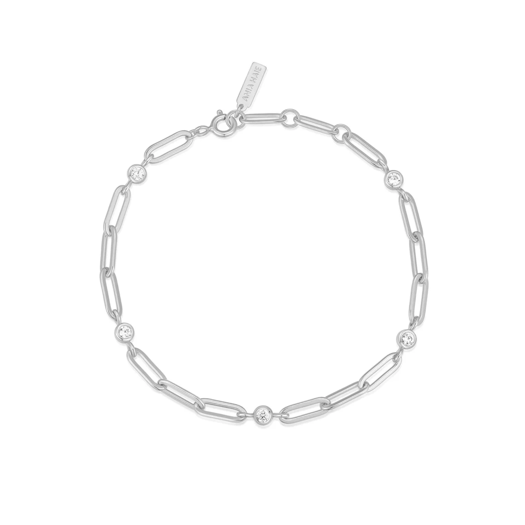 A silver paperclip chain bracelet with small clear gemstone accents at intervals, displayed on a clean white background. A brand tag is visible near the clasp.