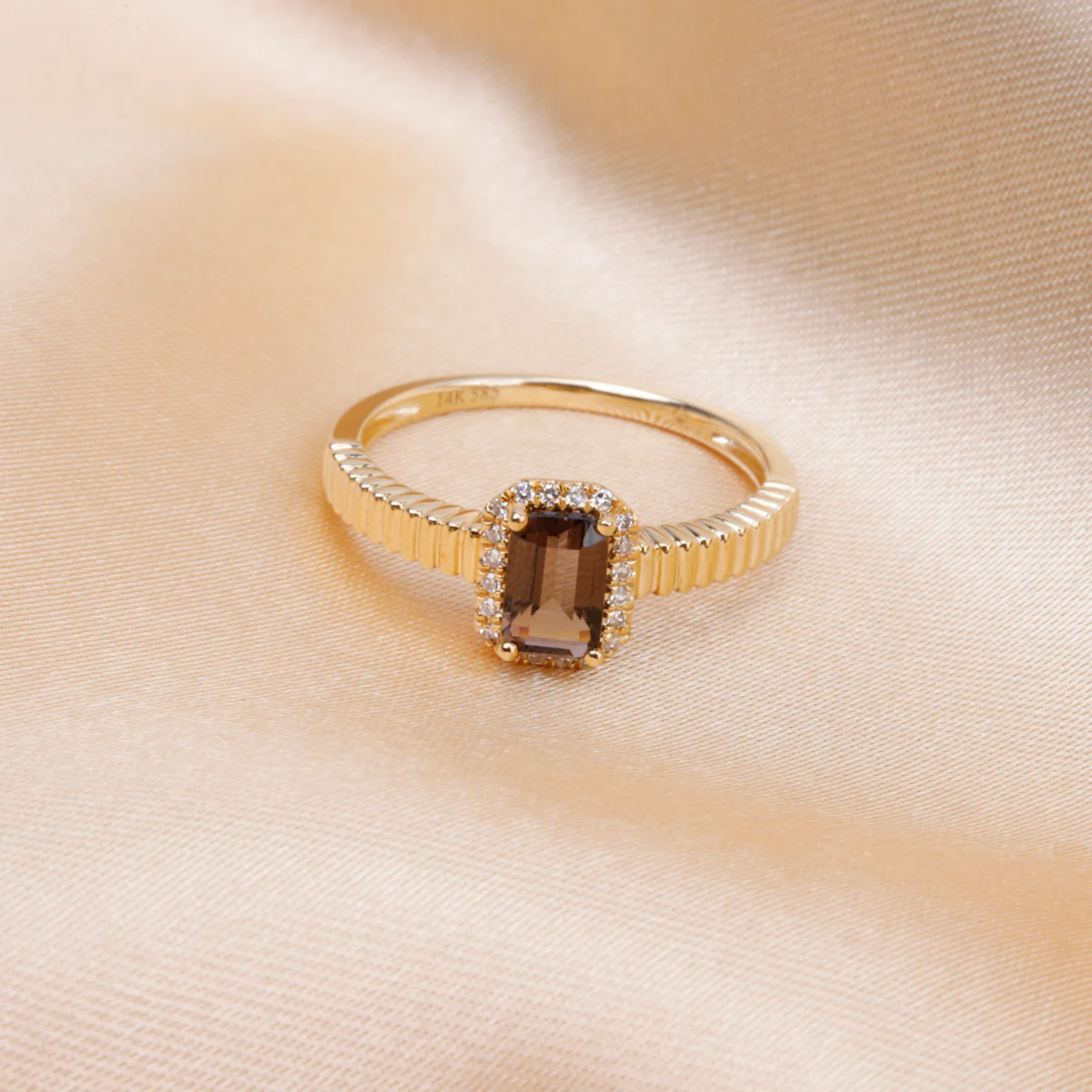 Gold ring with a smoky topaz stone on a beige fabric background